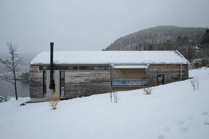 BAL — boligen sett langs skråningen med fjorden og fjellet bak, i snødrev
