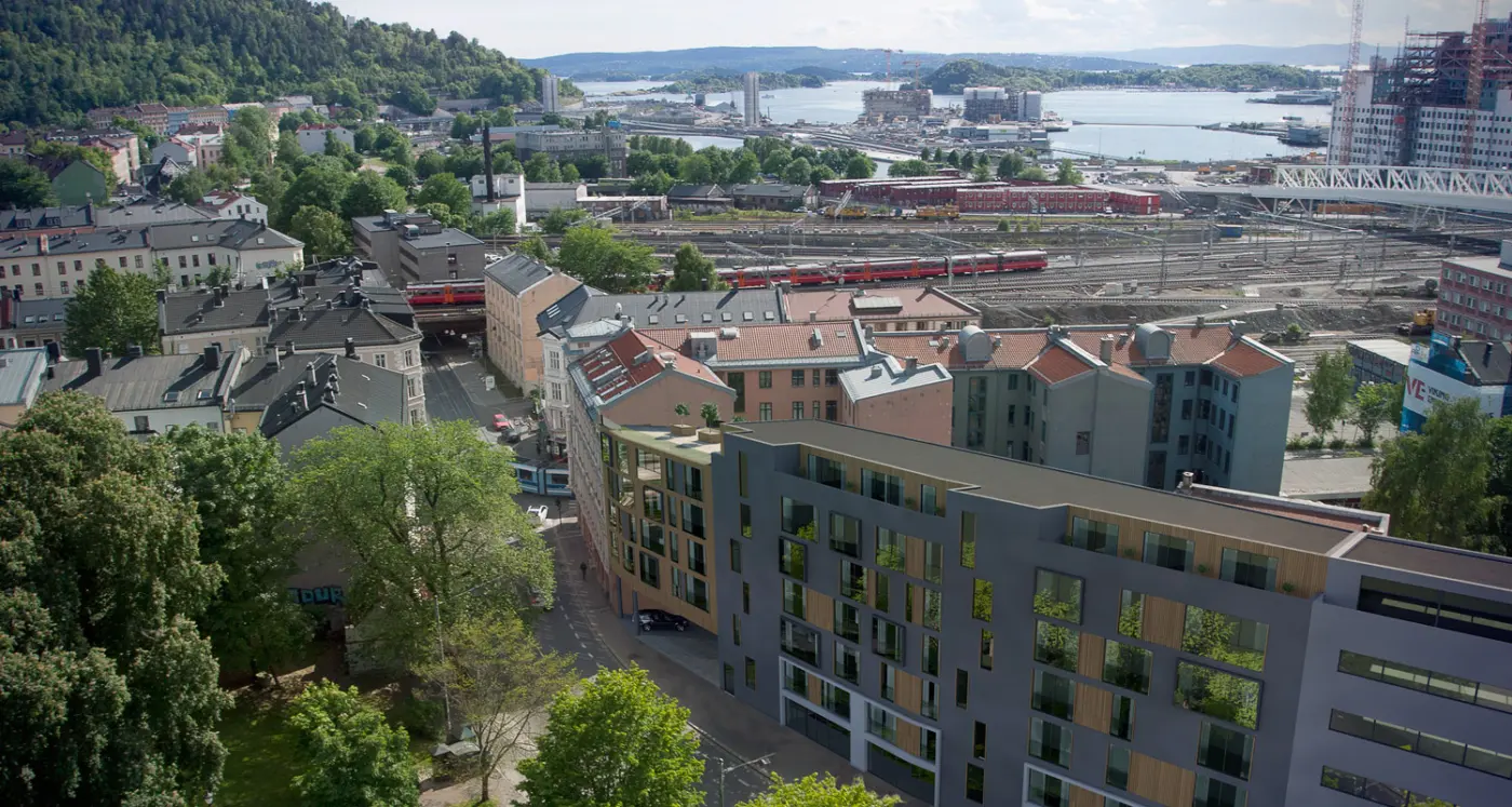 GRØ73 — leilighetsbygg i bykvartal sett ovenfra, med jernbanespor og fjorden i bakgrunnen. Illustrasjon