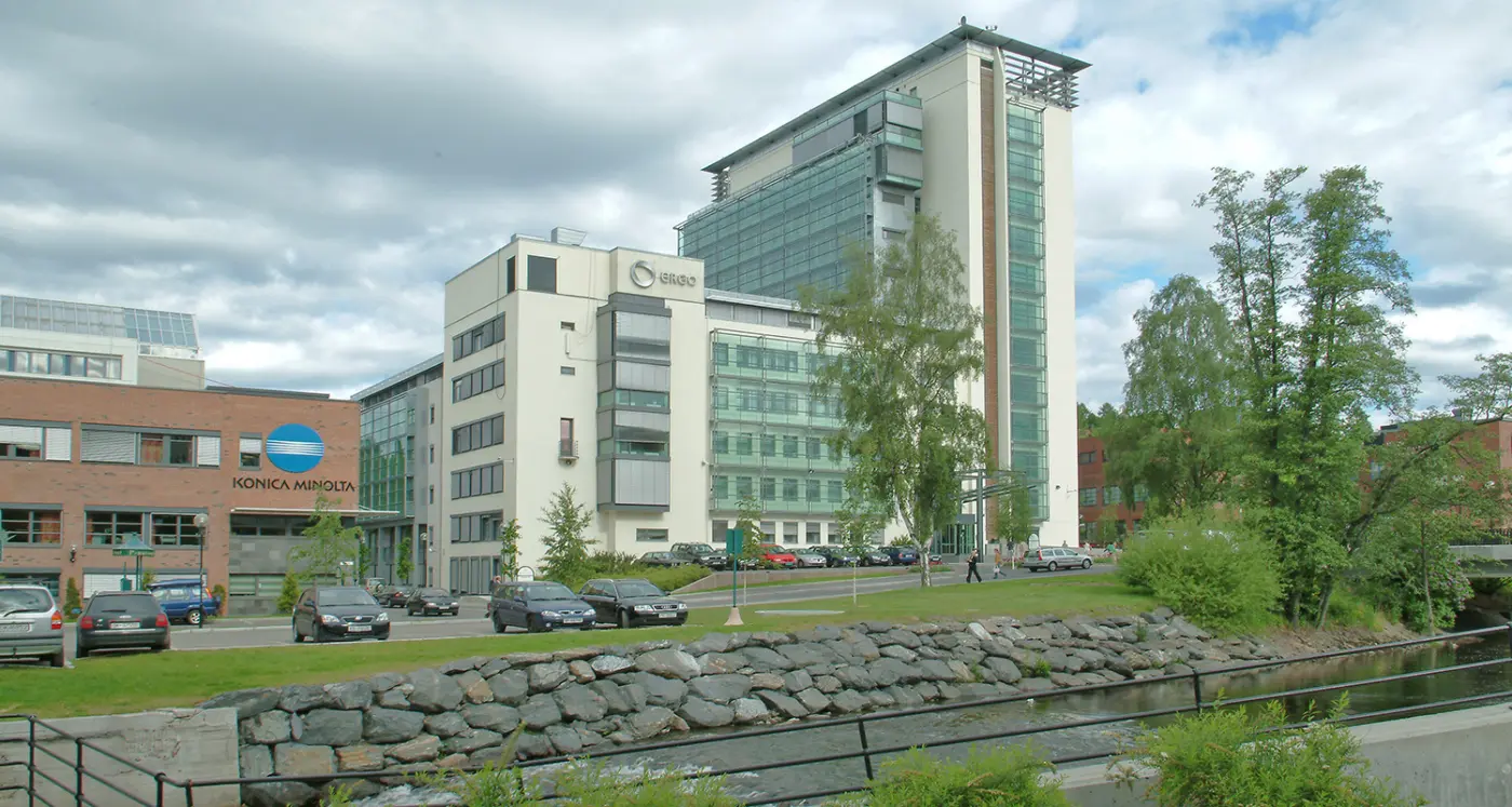NDV28 — kontorbygg i glass og puss langs elva i Nydalen, med steinsatt elvebredd i forgrunnen