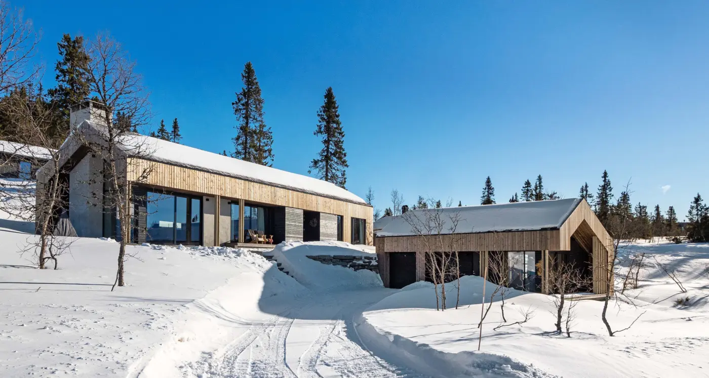 BET125 — hytte med frittliggende anneks i lys trekledning, i snødekt fjellterreng med skispor
