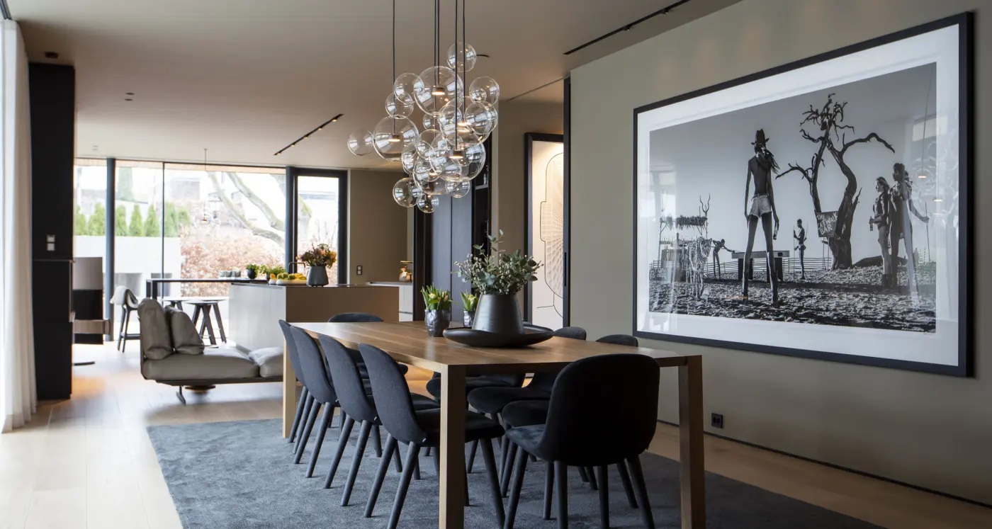 ABV16 — spisestue med langbord i eik og boblelampe, med stort fotografi på veggen og åpning mot kjøkken