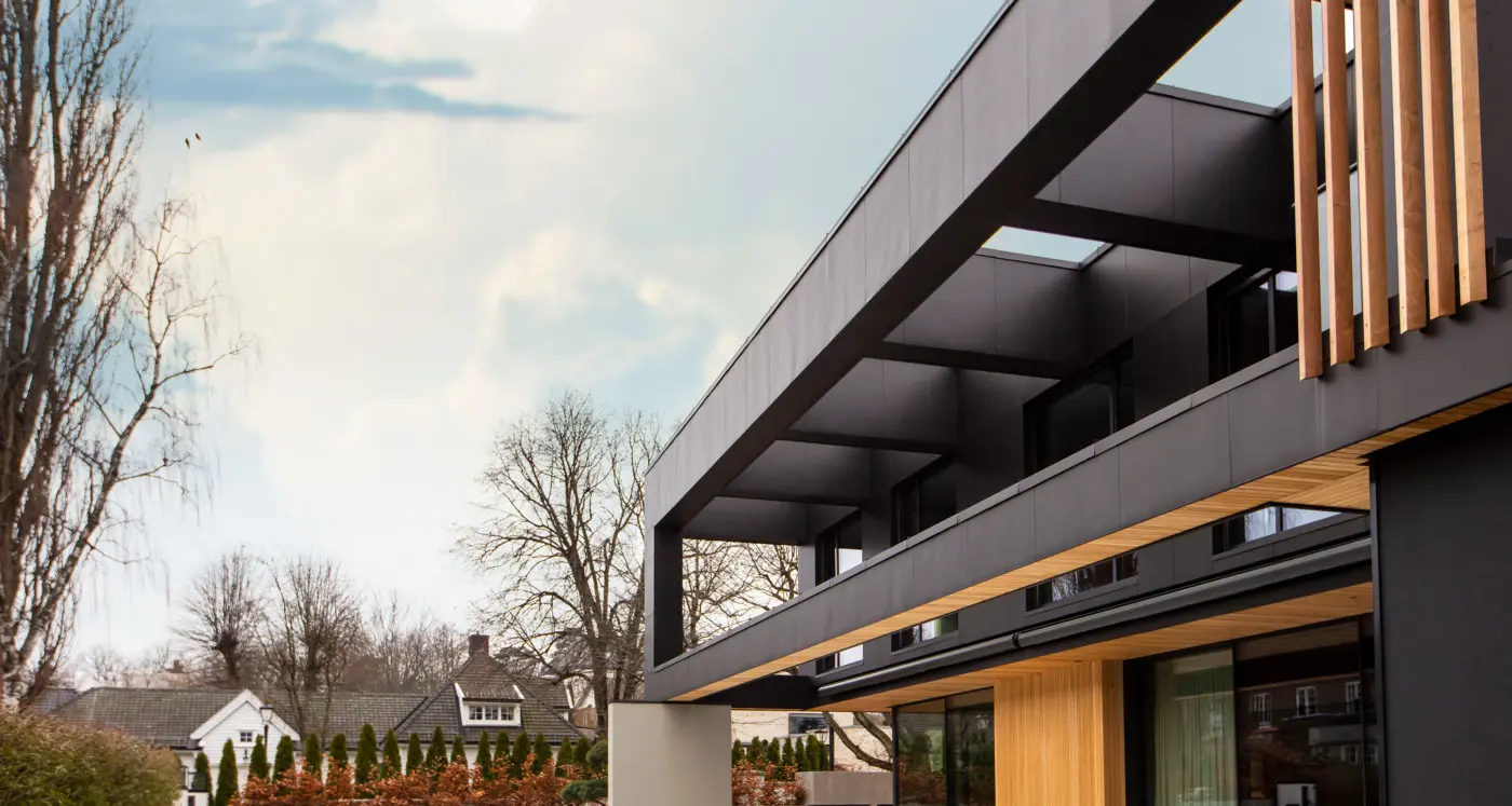 ABV16 — bolig med utkraget overetasje i mørk platekledning, med spilevegg i eik og store glassflater