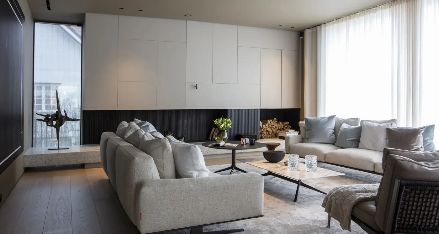 ABV16 — stue med hvit skapvegg over sortmalt peisvegg, benk i terrazzo og skulptur ved vinduet