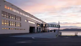 HRT — Hurtigruteterminalen i lys tegl med gangbro til kai, fotografert i solnedgang