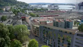 GRØ73 — leilighetsbygg i bykvartal sett ovenfra, med jernbanespor og fjorden i bakgrunnen. Illustrasjon
