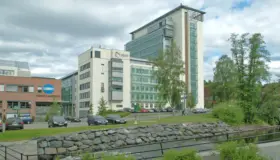 NDV28 — kontorbygg i glass og puss langs elva i Nydalen, med steinsatt elvebredd i forgrunnen