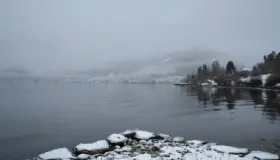 BAL — utsikt over fjorden mot bygda, med snødekte steiner i forgrunnen
