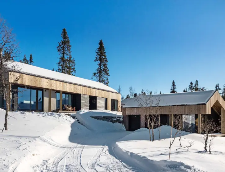 BET125 — hytte med frittliggende anneks i lys trekledning, i snødekt fjellterreng med skispor