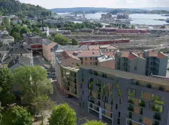 GRØ73 — leilighetsbygg i bykvartal sett ovenfra, med jernbanespor og fjorden i bakgrunnen. Illustrasjon