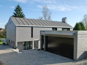 GDV214 — bolig i grå trekledning med saltak i båndtekket metall og tilbygd garasje