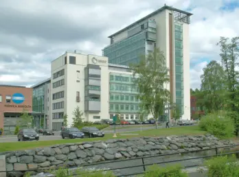 NDV28 — kontorbygg i glass og puss langs elva i Nydalen, med steinsatt elvebredd i forgrunnen