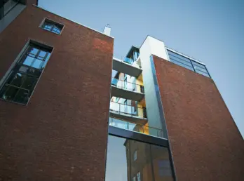 HAU16 — teglfasade sett nedenfra, med balkonger i en innskåret sjakt mellom bygningsvolumene